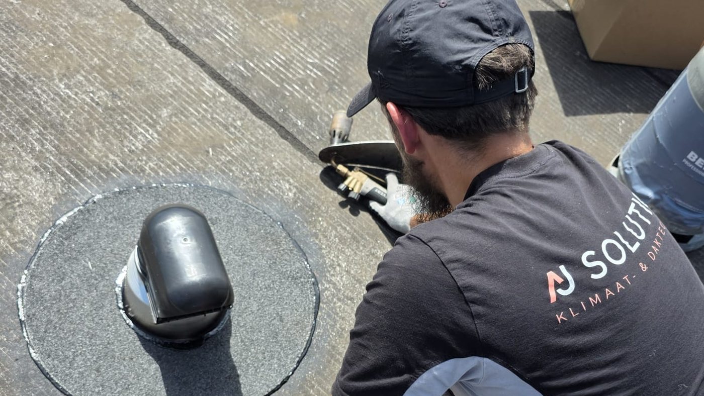 Dakspecialist van AJ Solution voert een reparatie uit op een plat dak