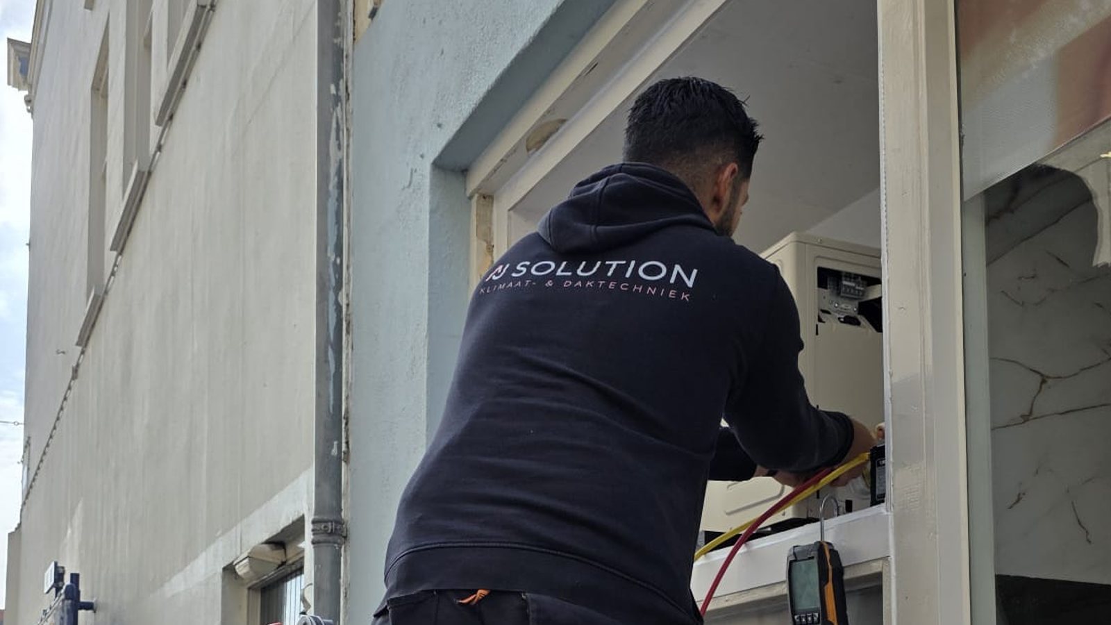 Monteur van AJ Solution meet de koelmiddeldruk van een aircosysteem