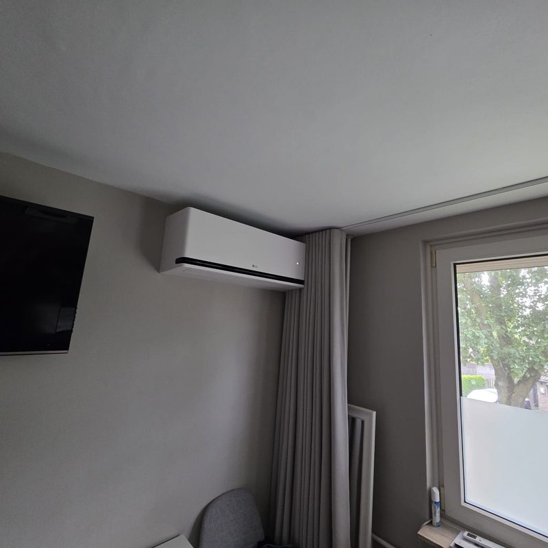 LG binnenunit naast een wandtelevisie in een woonkamer